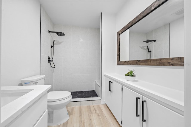 bathroom with vanity, hardwood / wood-style flooring, toilet, and tiled shower