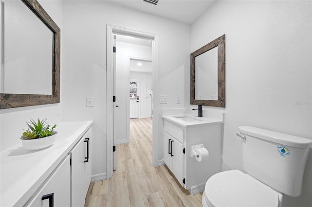 bathroom with wood-type flooring, toilet, and vanity