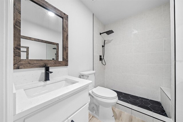 bathroom with tiled shower, vanity, and toilet