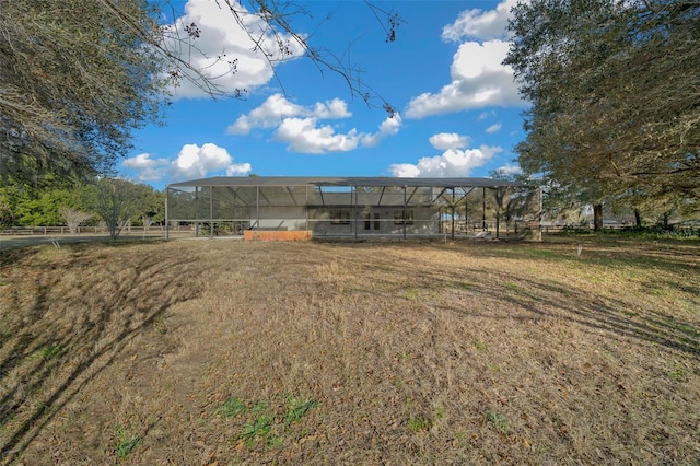 rear view of house with a rural view, a lanai, and a lawn