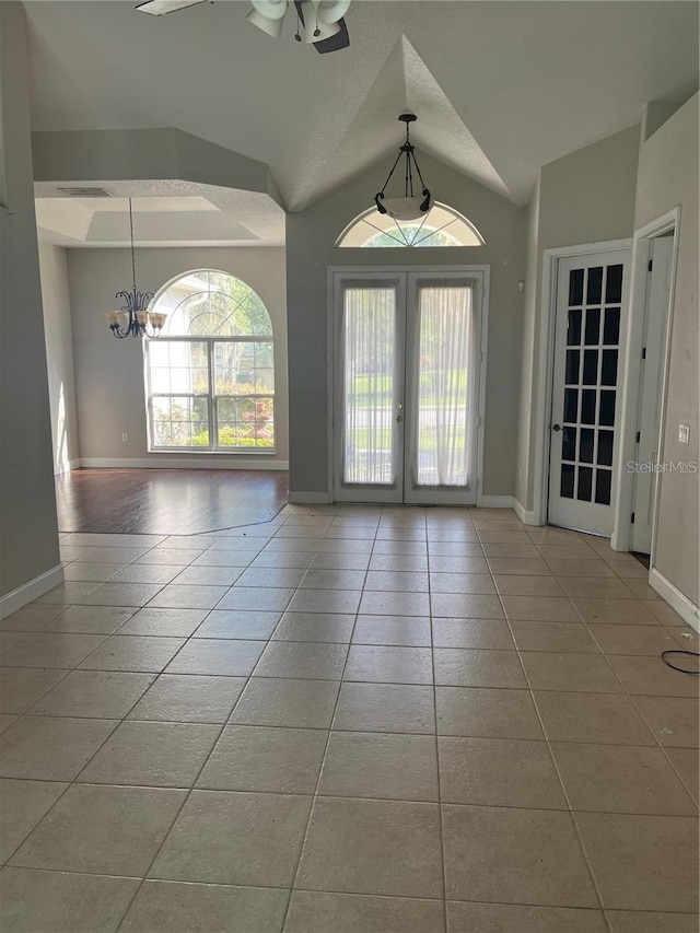 interior space featuring ceiling fan with notable chandelier, a wealth of natural light, french doors, and vaulted ceiling