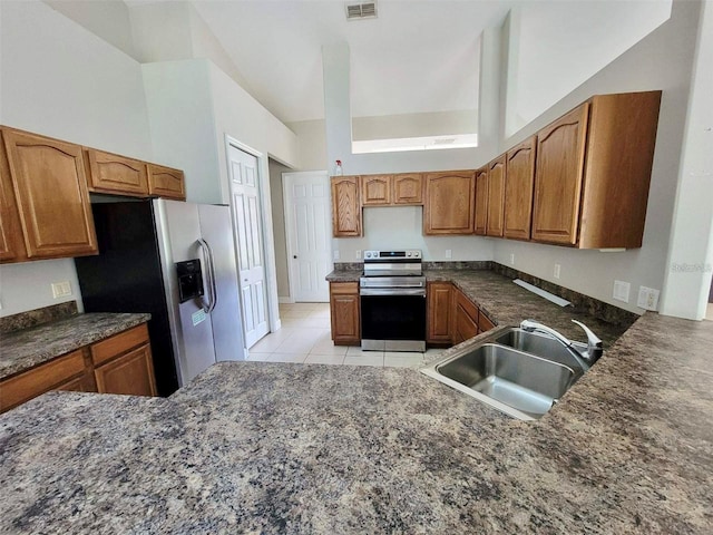 kitchen with sink, high vaulted ceiling, light tile patterned floors, appliances with stainless steel finishes, and kitchen peninsula