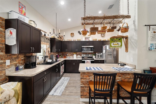 kitchen featuring appliances with stainless steel finishes, sink, backsplash, hanging light fixtures, and light hardwood / wood-style floors