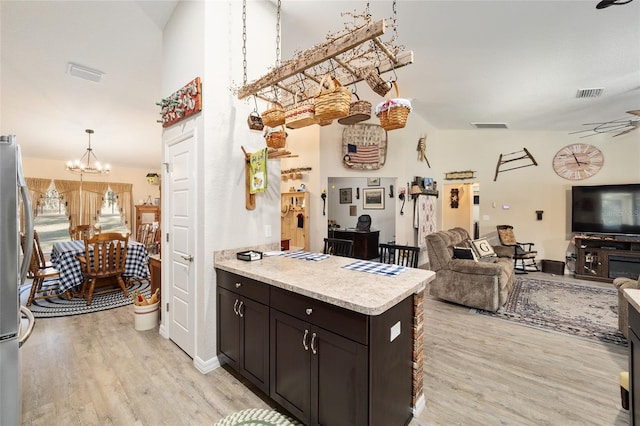 kitchen featuring high vaulted ceiling, stainless steel fridge, light hardwood / wood-style floors, and dark brown cabinets