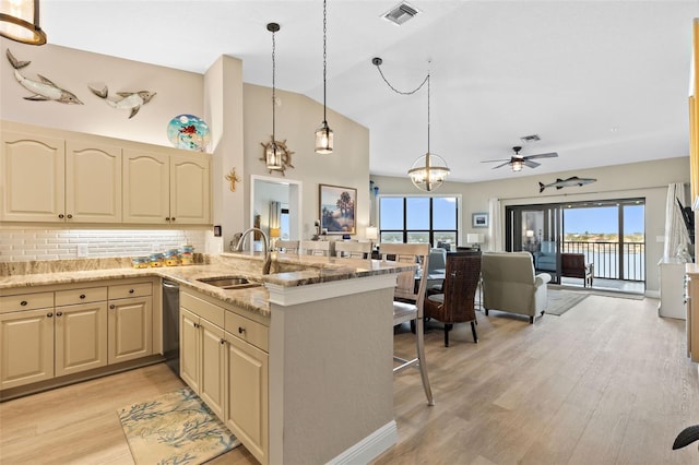 kitchen with sink, light stone counters, light wood-type flooring, kitchen peninsula, and pendant lighting