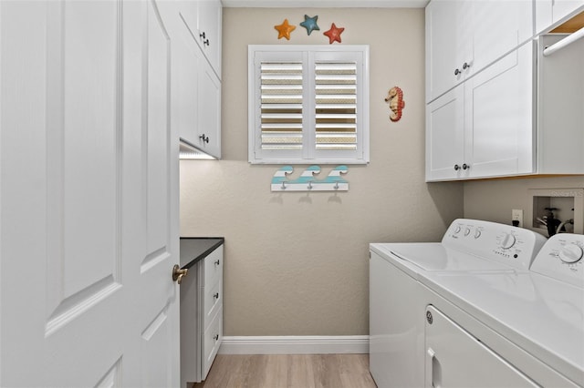 clothes washing area featuring cabinets, washing machine and clothes dryer, and light hardwood / wood-style flooring