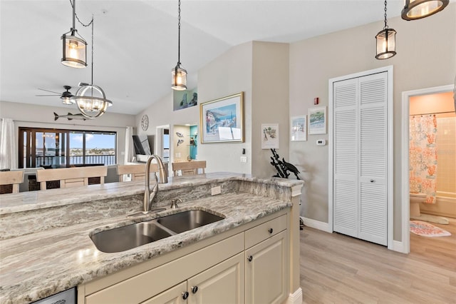 kitchen featuring hanging light fixtures, sink, and light stone counters