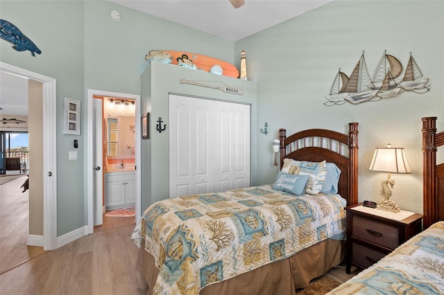 bedroom featuring vaulted ceiling, a closet, sink, ensuite bath, and light hardwood / wood-style flooring