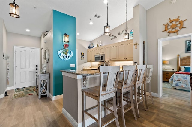 kitchen featuring dark stone countertops, hanging light fixtures, a breakfast bar area, and kitchen peninsula