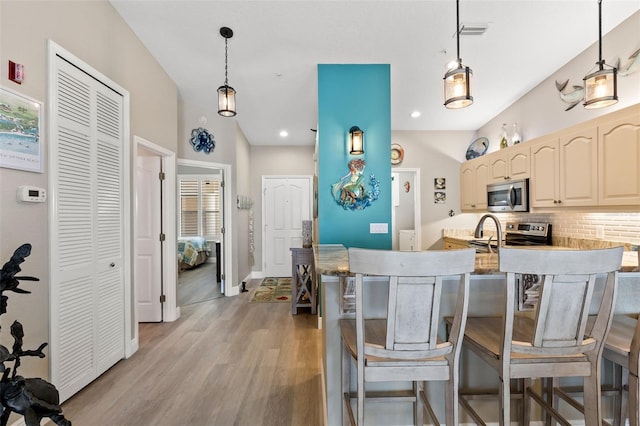 kitchen with pendant lighting, stainless steel appliances, tasteful backsplash, and light wood-type flooring