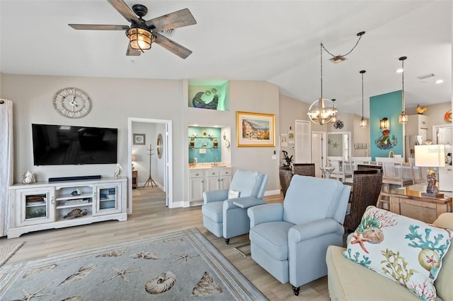 living room with vaulted ceiling, ceiling fan with notable chandelier, and light wood-type flooring