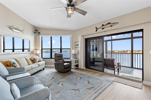 living room with ceiling fan, a water view, and light wood-type flooring