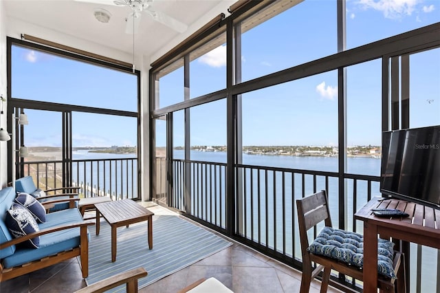 sunroom with ceiling fan and a water view