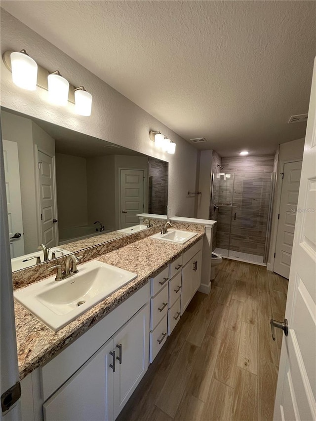 bathroom featuring hardwood / wood-style flooring, vanity, a shower with shower door, and a textured ceiling