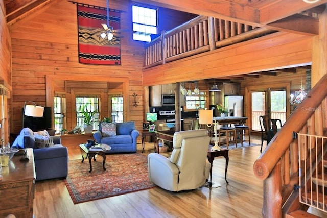 living room with ceiling fan, hardwood / wood-style floors, and wooden walls