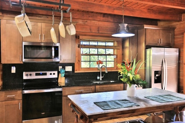 kitchen featuring sink, hanging light fixtures, stainless steel appliances, tasteful backsplash, and dark stone counters