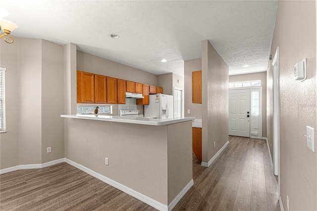 kitchen featuring range, a textured ceiling, kitchen peninsula, hardwood / wood-style flooring, and white refrigerator with ice dispenser