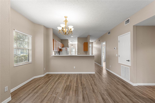 spare room featuring wood-type flooring, a chandelier, and a textured ceiling