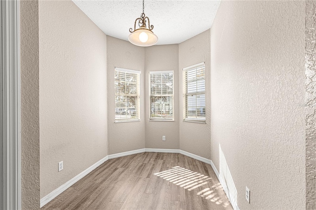 unfurnished room with hardwood / wood-style flooring and a textured ceiling