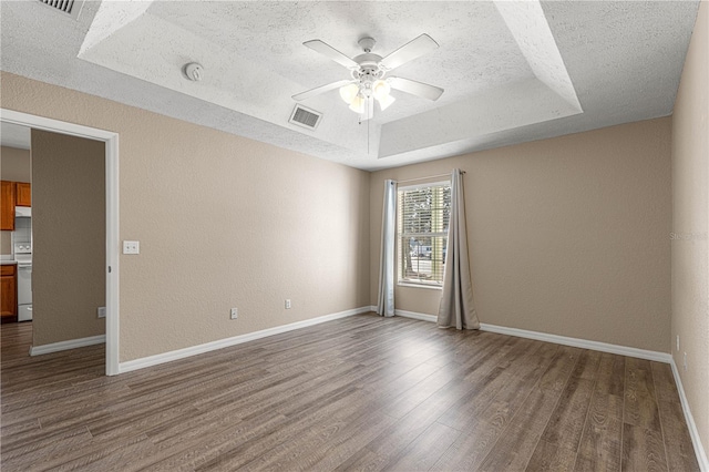 spare room with ceiling fan, a tray ceiling, a textured ceiling, and hardwood / wood-style flooring