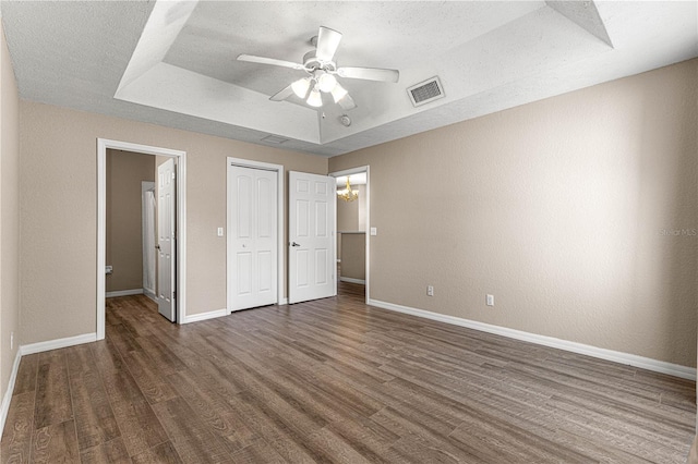 unfurnished bedroom with dark hardwood / wood-style flooring, a closet, a raised ceiling, and a textured ceiling