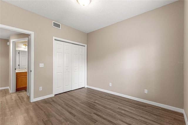 unfurnished bedroom with dark hardwood / wood-style flooring, a closet, and a textured ceiling