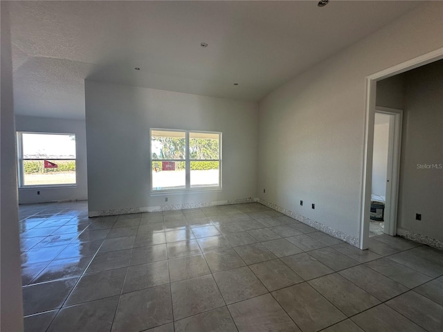 tiled empty room with plenty of natural light and a textured ceiling