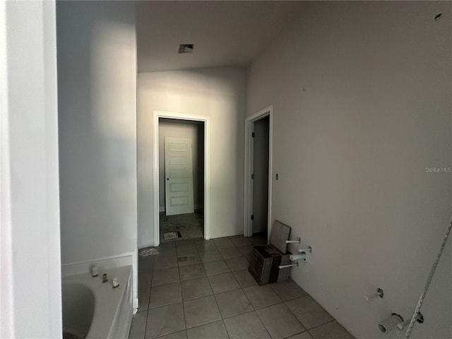 corridor featuring light tile patterned flooring and vaulted ceiling