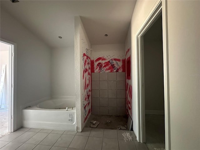 bathroom with a washtub and tile patterned flooring