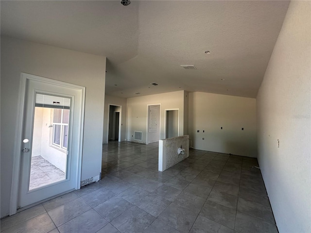 spare room with lofted ceiling and a textured ceiling