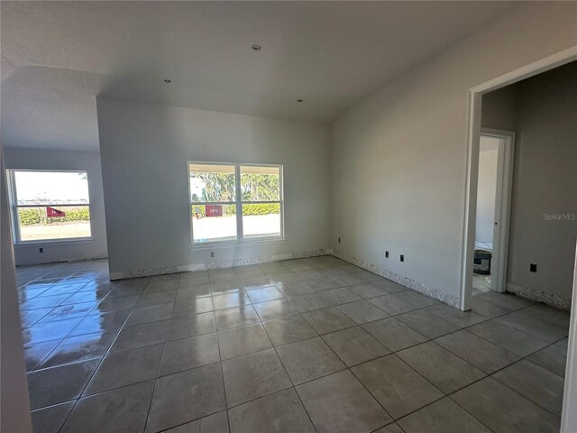 spare room with a wealth of natural light, tile patterned flooring, and baseboards