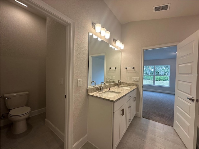 full bath with toilet, double vanity, a sink, and visible vents