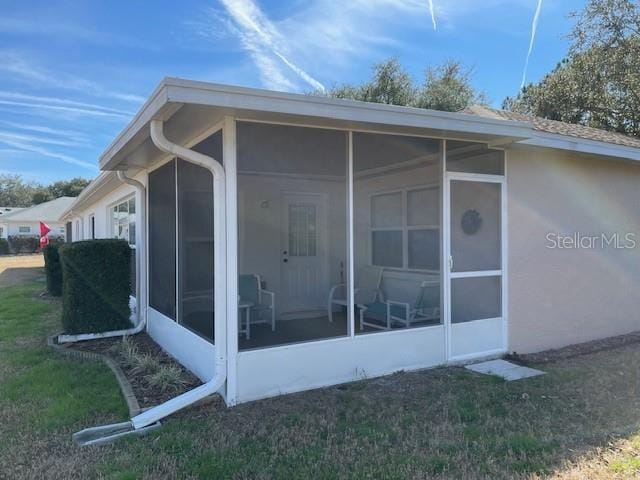 view of home's exterior with a yard and a sunroom