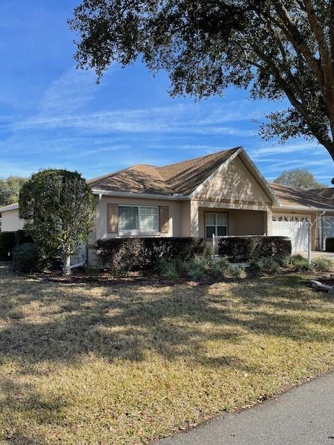 single story home featuring a garage, a front lawn, and stucco siding