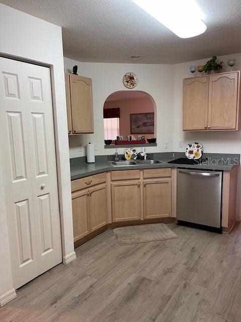 kitchen featuring a sink, dark countertops, dishwasher, and light brown cabinets