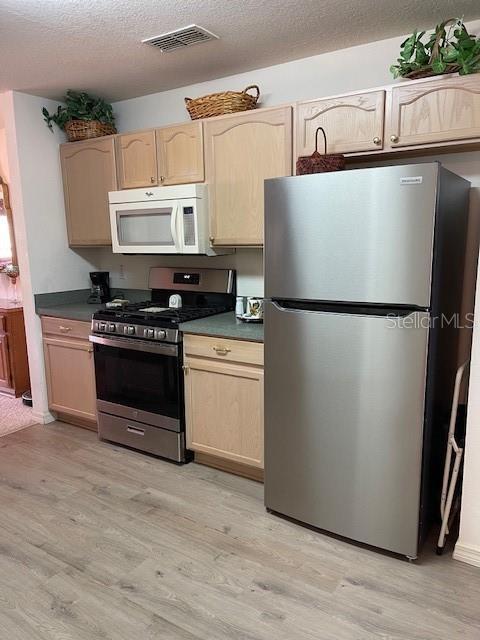 kitchen with visible vents, appliances with stainless steel finishes, light wood-style flooring, and light brown cabinets