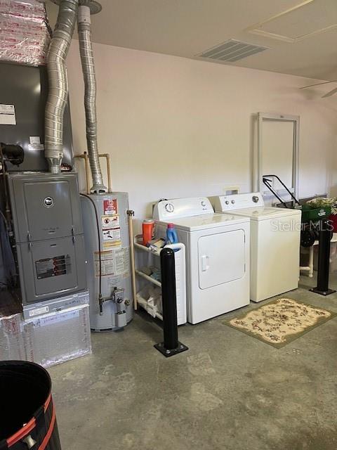 washroom featuring visible vents, water heater, laundry area, heating unit, and independent washer and dryer