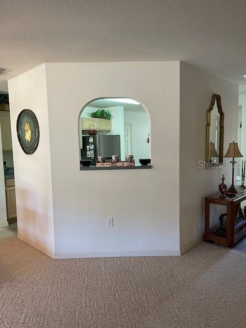 room details featuring black refrigerator, a textured ceiling, and carpet flooring