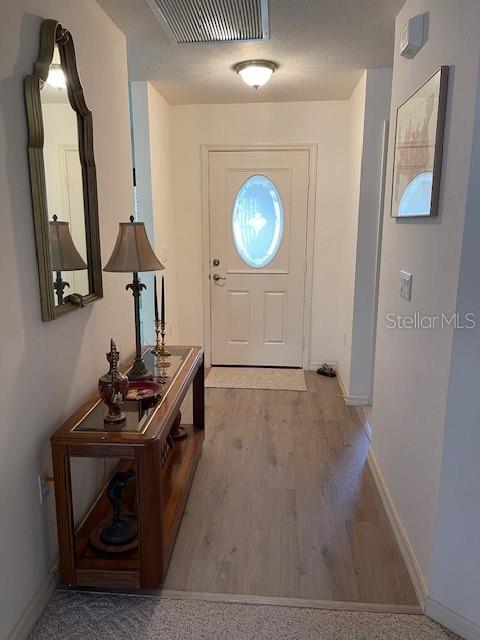 entryway with visible vents, baseboards, and wood finished floors