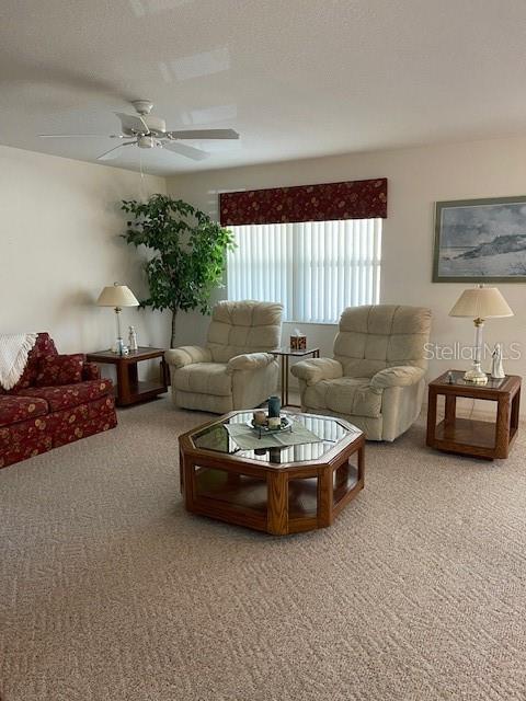 carpeted living room with a textured ceiling and ceiling fan