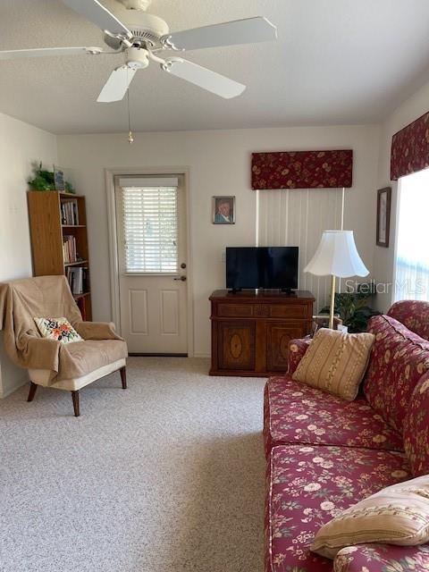 living room featuring light colored carpet and ceiling fan