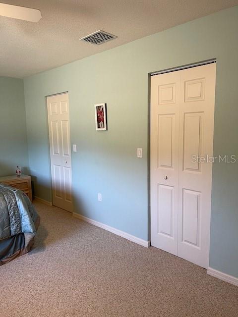 bedroom featuring baseboards, carpet, visible vents, and a textured ceiling