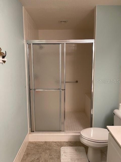 bathroom with vanity, baseboards, a stall shower, tile patterned floors, and toilet