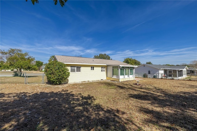 rear view of house featuring a sunroom and a yard