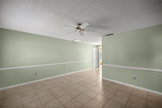 tiled empty room with ceiling fan with notable chandelier and a textured ceiling