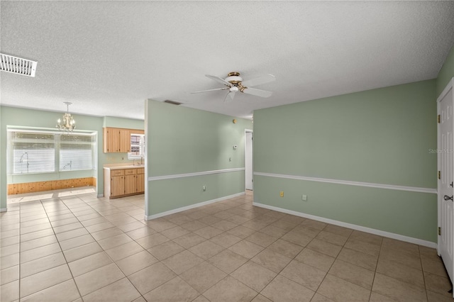 tiled empty room featuring ceiling fan with notable chandelier and a textured ceiling