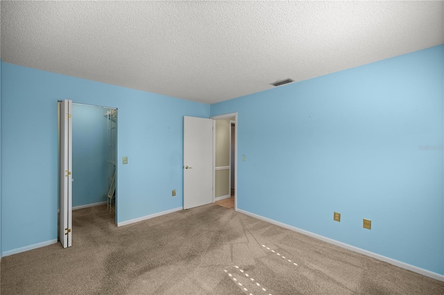 unfurnished bedroom featuring a closet, a spacious closet, carpet, and a textured ceiling