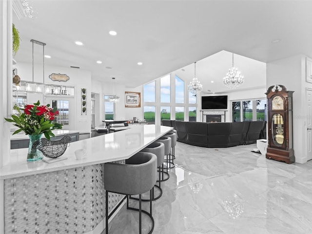 kitchen featuring pendant lighting, a wealth of natural light, a breakfast bar, and a notable chandelier