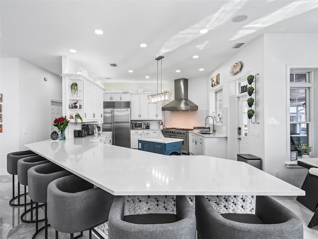 kitchen with decorative light fixtures, high quality appliances, a breakfast bar area, kitchen peninsula, and wall chimney range hood