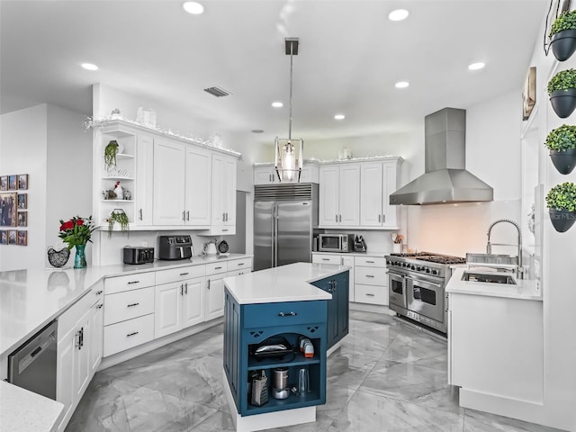 kitchen with wall chimney range hood, premium appliances, white cabinets, and a center island